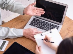 ノートパソコンとクリップボードで打ち合わせする様子