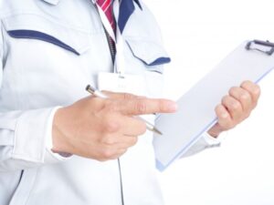 指差しをして確認をする作業服姿の男性